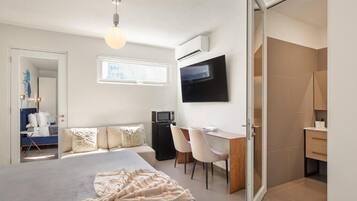 A modern bedroom with a large bed, a desk, and a TV.
