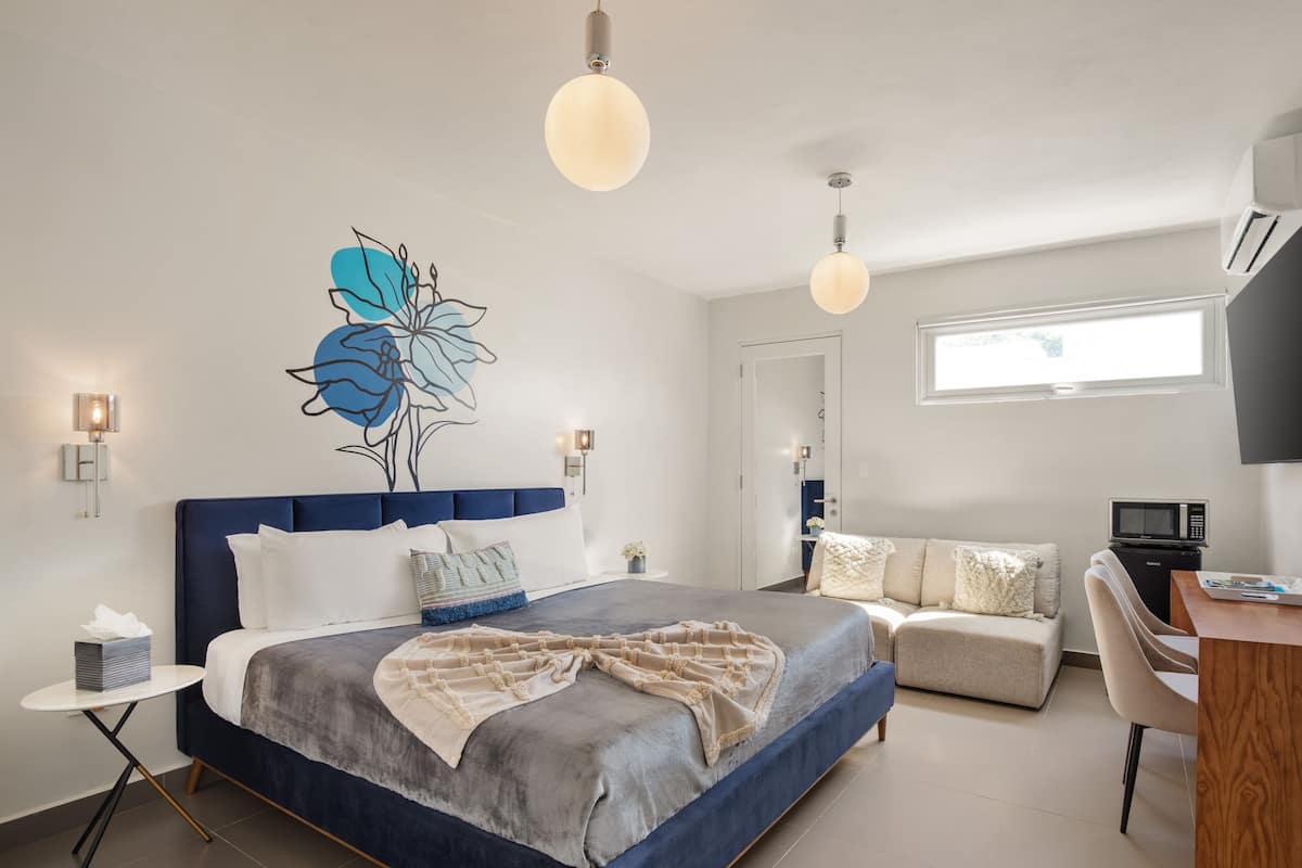 A modern bedroom with a large bed, bedside tables, a desk, and a chair.