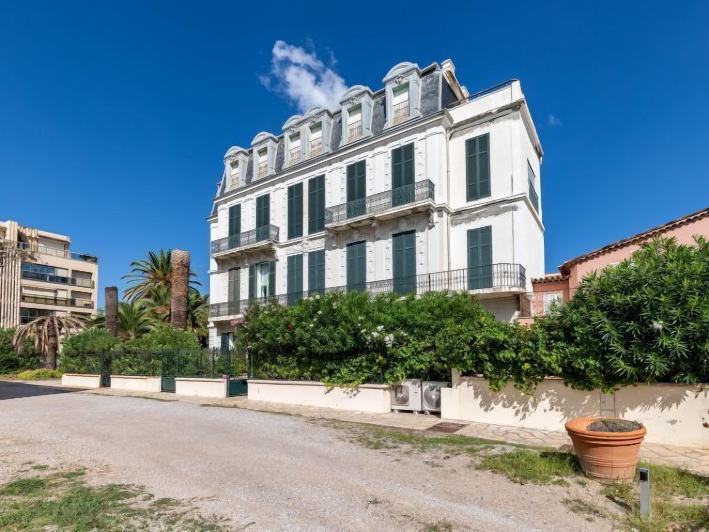Un edificio a più piani con facciata simmetrica, ampie finestre e un balcone al piano superiore.