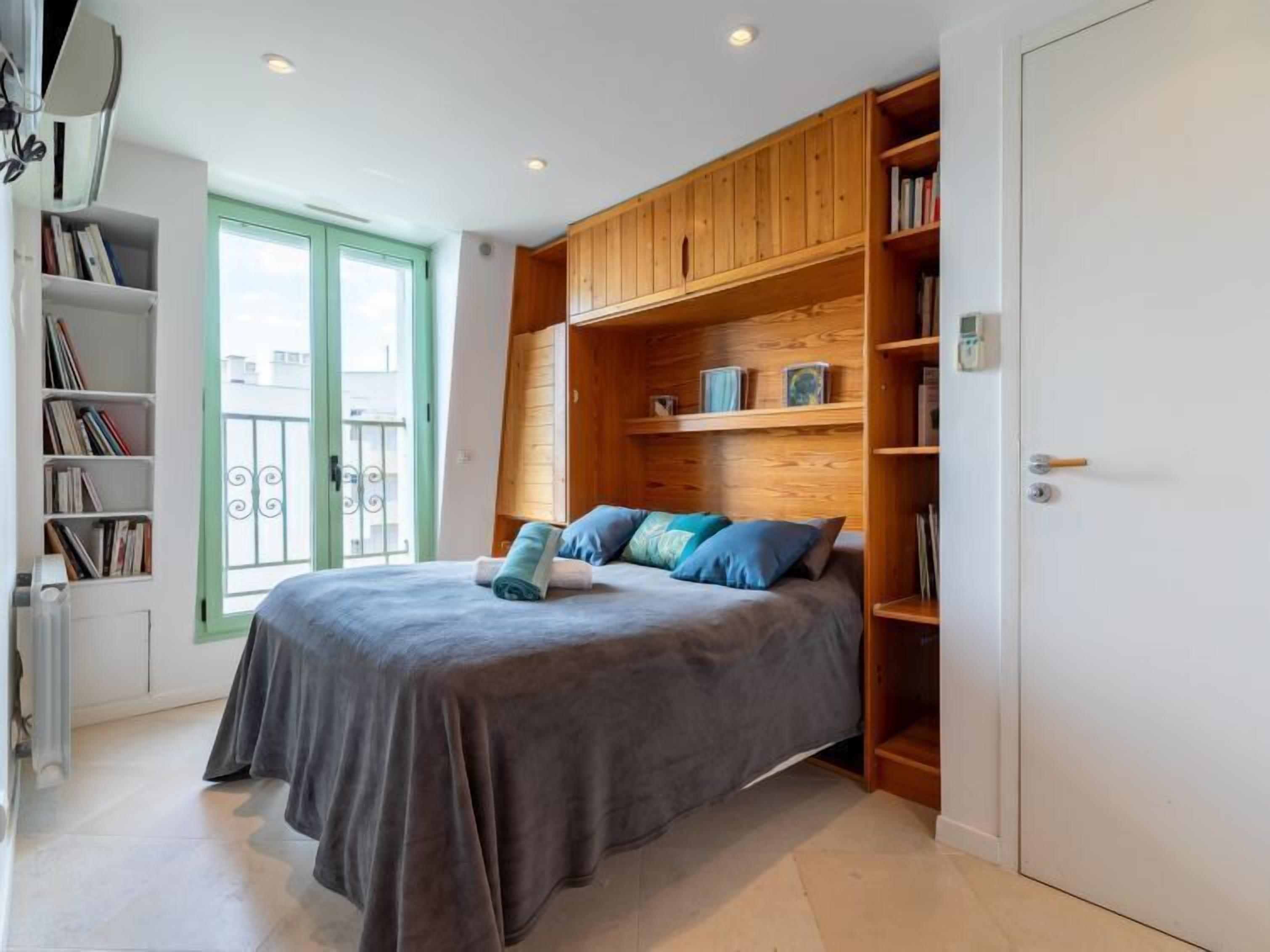 A bedroom with a bed, a bookshelf, and a door.
