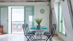A dining area with a table and four chairs, a potted plant, and a clock on the wall.