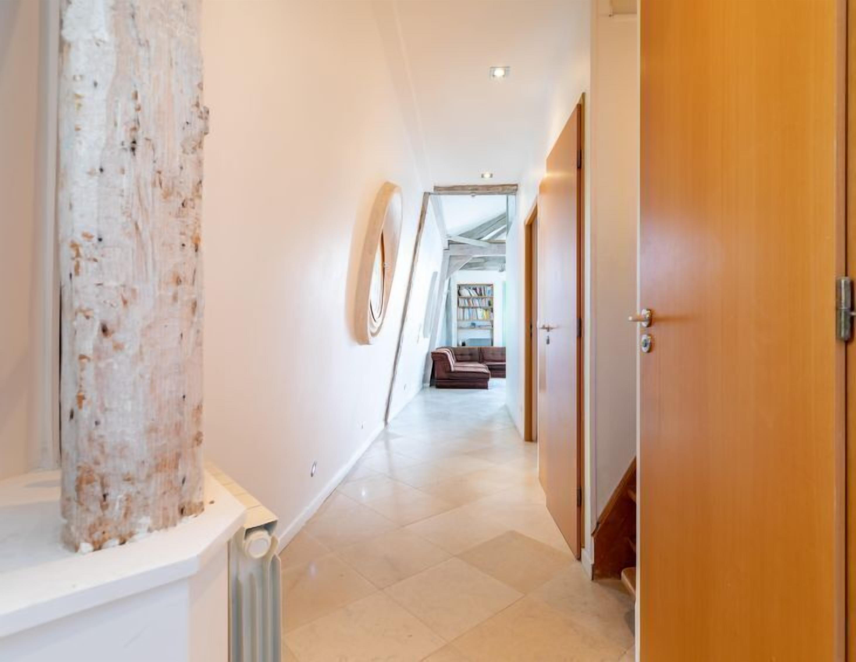 A modern hallway with a white wall, a wooden door, and a radiator.