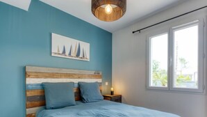 A bedroom with a bed, a nightstand, a wall-mounted painting, and a window with a view. - Petite Dépée by Interhome (Grayan et L' Hopital)