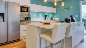 A modern kitchen with stainless steel appliances, a central island with bar stools, and pendant lighting. - Petite Dépée by Interhome (Grayan et L' Hopital)