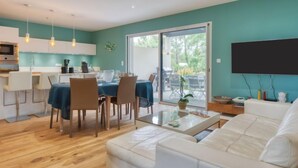 A modern living room with a white sofa, a dining area with a table set for four, and a kitchen with a microwave and cabinets. - Petite Dépée by Interhome (Grayan et L' Hopital)