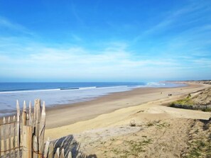 A beach with a wooden fence in the foreground, a sandy shore, and the ocean in the background. - Petite Dépée by Interhome (Grayan et L' Hopital)