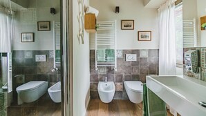 Ein modernes Badezimmer mit zwei Toiletten, einer Dusche und einem Waschbecken.