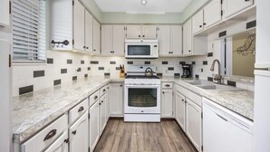 A kitchen with white cabinets, a microwave, stove, and a sink. - Spacious multi-unit retreat in Rockford (Rockford)