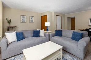 A living room with two grey sofas, a white coffee table, and a blue lamp. - Spacious multi-unit retreat in Rockford (Rockford)