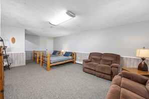 Une pièce comprenant un lit, deux canapés, une lampe et un luminaire au plafond.