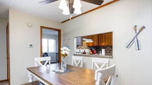 A dining area with a wooden table and white chairs, a kitchen with wooden cabinets, and a ceiling fan. - Spacious multi-unit retreat in Rockford (Rockford)