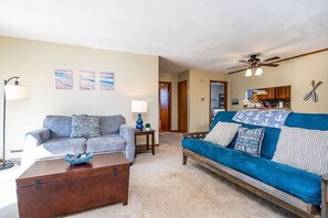 A living room with a blue sofa, a grey sofa, a wooden coffee table, and a lamp.