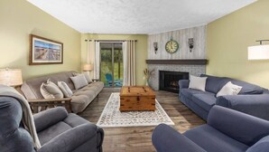 A living room with a fireplace, two sofas, a wooden coffee table, and a large window with curtains. - Spacious multi-unit retreat in Rockford (Rockford)