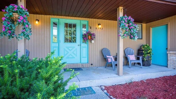 A wooden porch with a turquoise door, two chairs, hanging flower baskets, and a small table. - Spacious multi-unit retreat in Rockford (Rockford)
