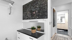 A modern bathroom with a blackboard wall, a white vanity, two potted plants, and a mirror.