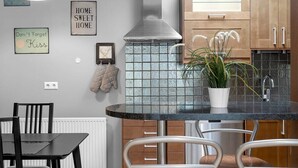 A kitchen with a black countertop, white chairs, and a potted plant.