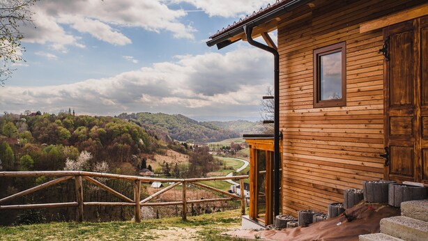 Una cabaña de madera con vistas a un valle y colinas.