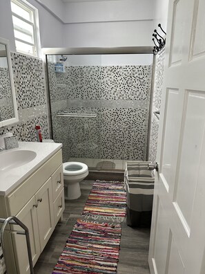 Une salle de bain avec un lavabo blanc, des toilettes et un espace douche.
