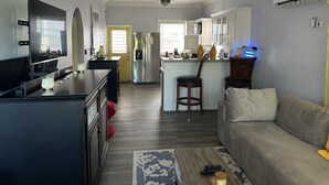 Eine moderne Küche mit Kühlschrank, Mikrowelle und einer Essecke mit Bar. Es gibt ein Wohnzimmer mit Sofa und Couchtisch.