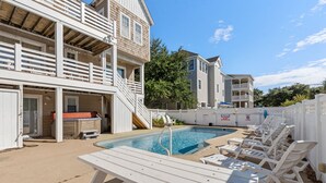 A pool area with lounge chairs and a hot tub, surrounded by a wooden deck and a white fence. - Pirate's Booty: Private Pool | Hot Tub | Elevator (Nags Head)