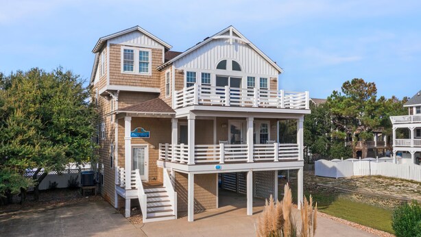 A two-story house with a balcony and a covered porch. - Pirate's Booty: Private Pool | Hot Tub | Elevator (Nags Head)