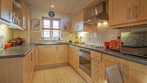 A kitchen with wooden cabinets, a stainless steel oven, and a microwave.
