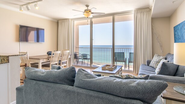 A spacious living room with a balcony, a ceiling fan, and a flat-screen TV.
