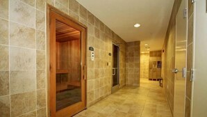 A corridor with a wooden elevator door, a tiled wall, and a tiled floor.