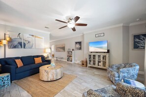 A modern living room with a blue sofa, a round coffee table, and a ceiling fan.