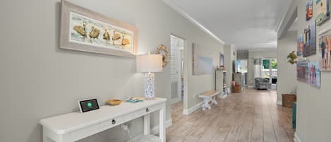 A hallway with a white console table, a framed picture of pelicans, and a decorative lamp.