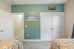 Ein Schlafzimmer mit zwei Betten, einem Strandbild und einem Schild mit der Aufschrift 'BEACH HOUSE'.