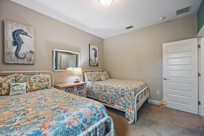 A bedroom with two beds, a nightstand, a dresser, and a door.