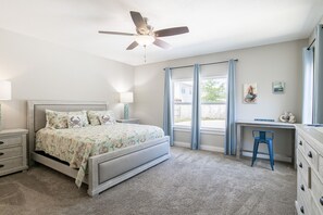 Relax in this serene bedroom with a large bed, desk, and ceiling fan, perfect for working or unwinding.