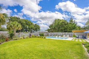 Ein Garten mit Swimmingpool, Holzzaun und einer Terrasse mit Sitzgelegenheiten.