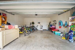 A garage with bicycles, a storage cabinet, and various items on shelves.