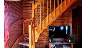 Una escalera de madera conduce a una sala de estar con televisor y mueble de almacenamiento.