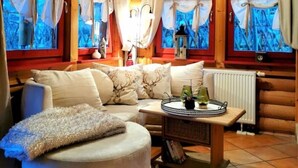 Interior acogedor de una cabaña de troncos, con un sofá, un otoman redondo y una mesita baja con una bandeja.