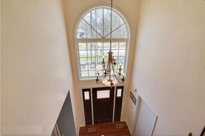 Enter a spacious entryway with a grand arched window and a classic chandelier.