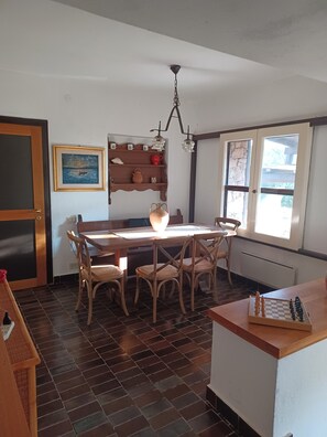 Un comedor con mesa y sillas de madera, una araña y una ventana con vistas.
