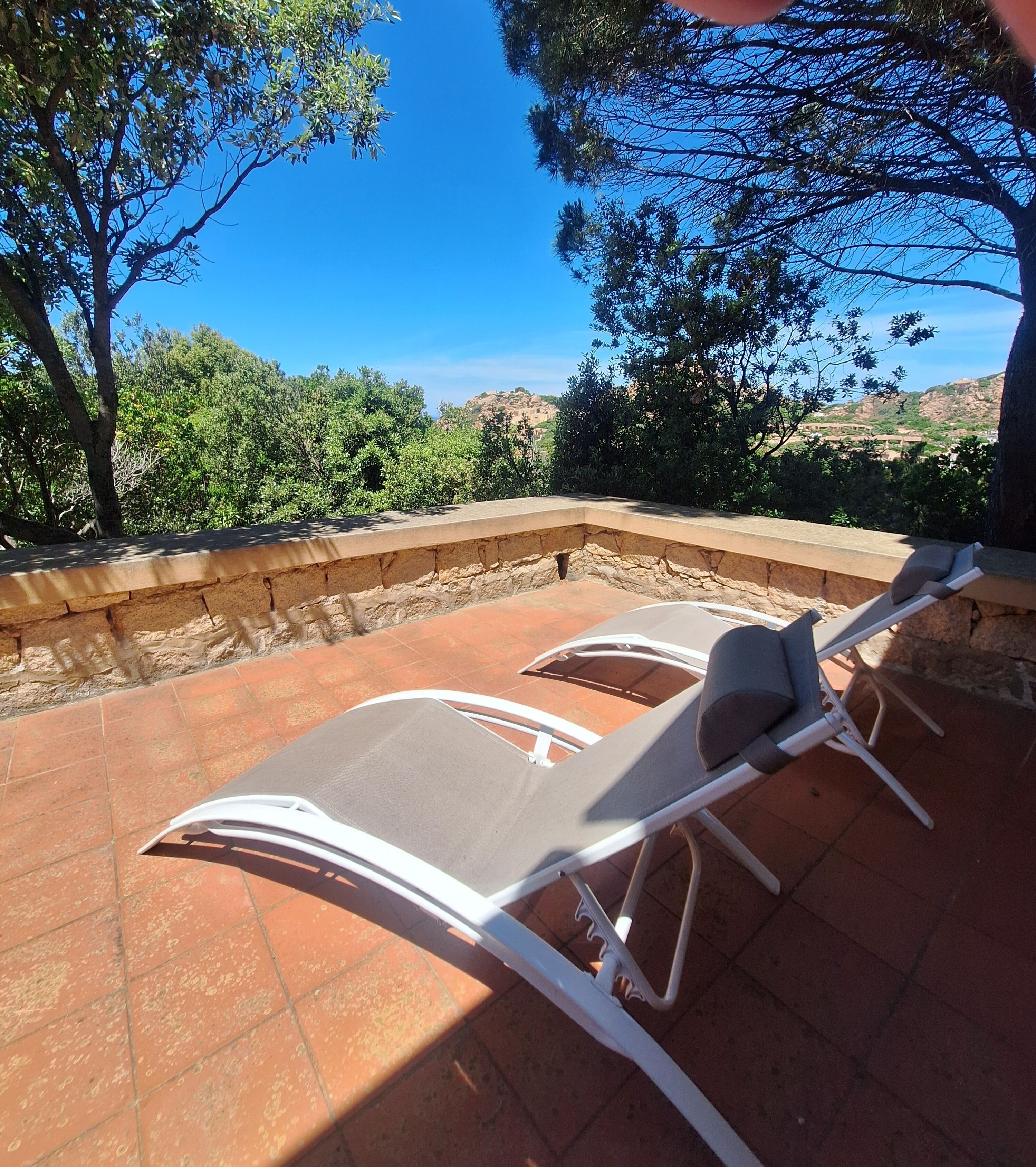Eine Terrasse mit einer Steinmauer und Blick auf eine gebirgige Landschaft.
