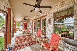 Ein überdachter Patio-Bereich mit Steinmauern, Holzschaukelstühlen, einem Deckenventilator und Blick ins Freie.