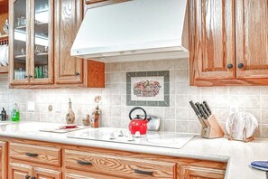 A kitchen with wooden cabinets, a white stove, and a tiled backsplash.