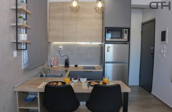 A modern kitchen with a wooden countertop, two black chairs, a microwave, a refrigerator, and a coffee maker.