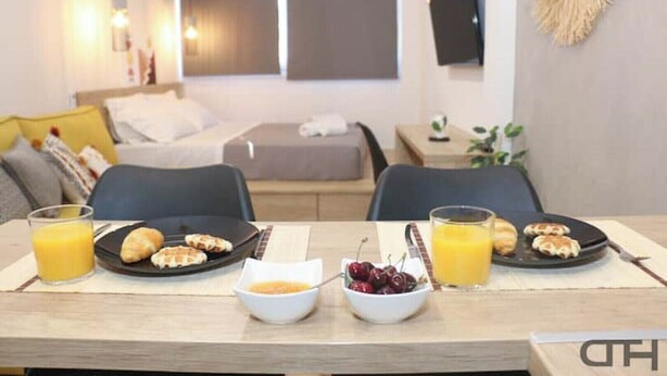 Een ontbijt met croissants, kersen en jus d'orange op een tafel in een moderne hotelkamer.