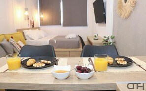 A breakfast setup with croissants, cherries, and orange juice on a table in a modern hotel room.