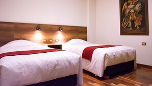Ein Hotelzimmer mit zwei Betten, einem Holzkopfende, Nachttischlampen und einem Bild an der Wand.