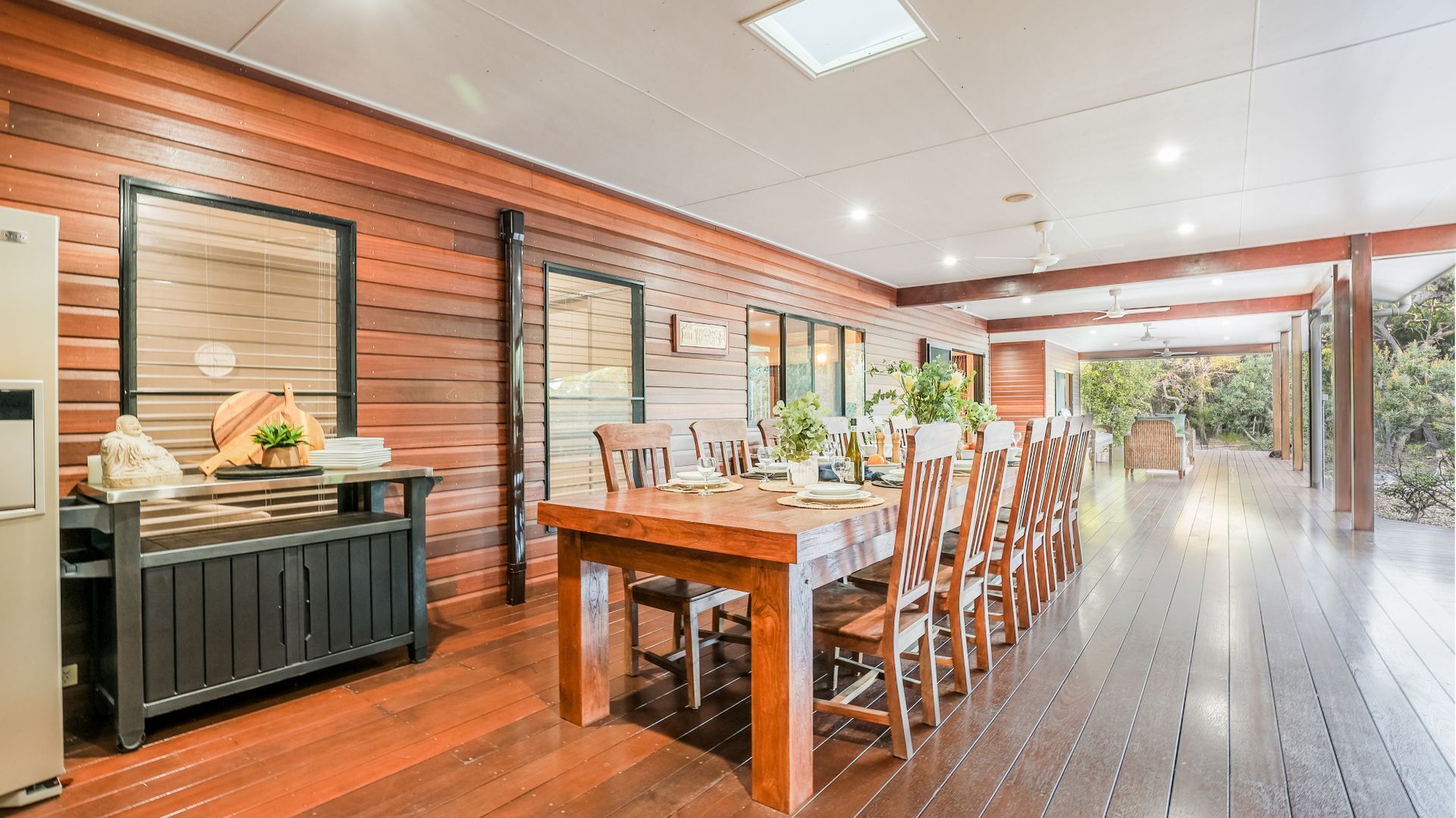 A spacious dining area with a long wooden table and chairs, large windows, and a view of the outdoors.