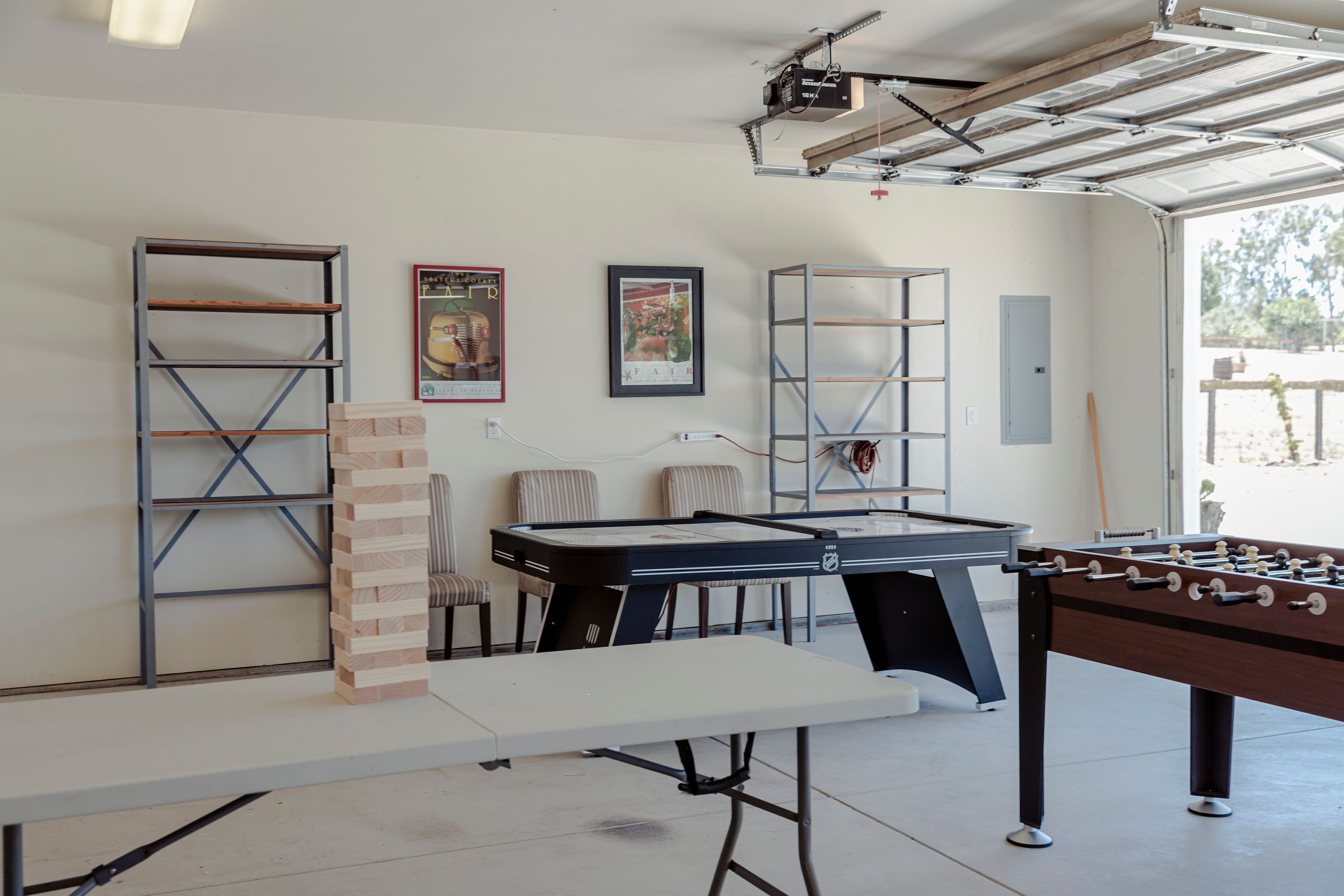 Une pièce équipée d’un baby-foot, d’une table de billard et d’une table de ping-pong. On y trouve également des chaises et un petit pilier en briques.