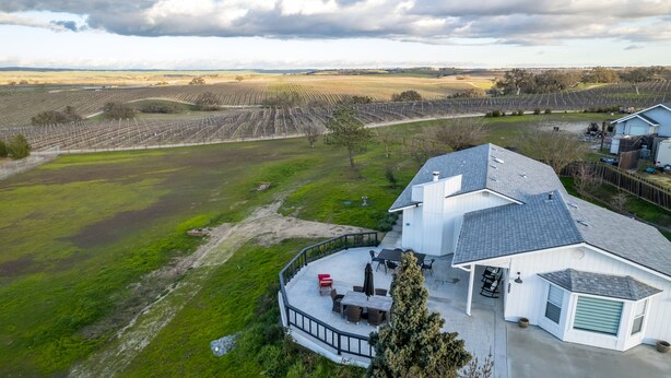 Ein Haus mit einer großen Terrasse, einer Garage und Blick auf einen Weinberg.