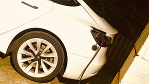 A white car parked next to a building with a visible door and a cable connected to the car. - Spacious and bright apartment surrounded by greenery 10 minutes from Varese (Valganna)